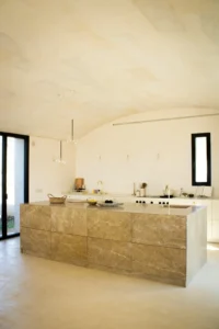 Isla central de mármol beige en un espacio amplio con estilo mediterráneo